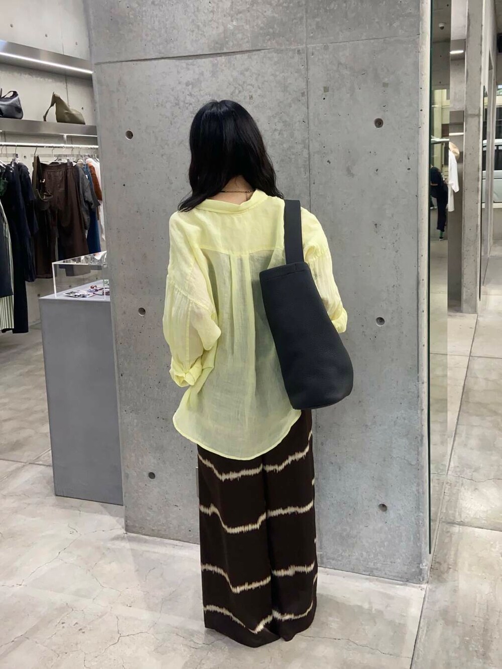 ブラック系のトートバッグ、ブラウン系のその他パンツ、イエロー系のシャツ/ブラウスを着用したレディースの夏コーディネートの3枚目の写真