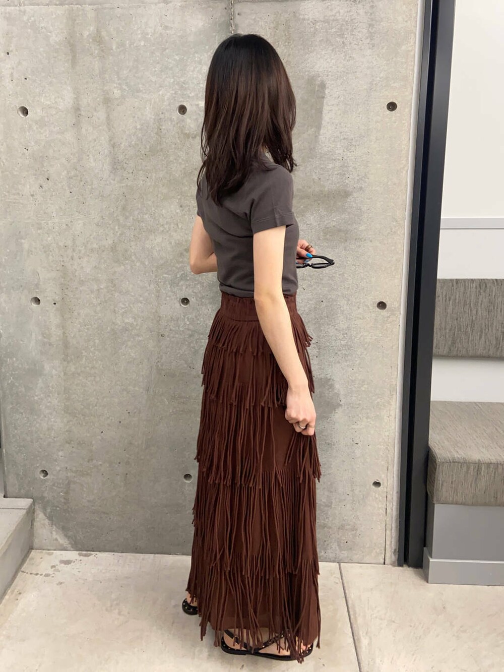 ブラウン系のスカート、ブラック系のサンダル、ブラック系のメガネを着用したレディースの春コーディネートの2枚目の写真