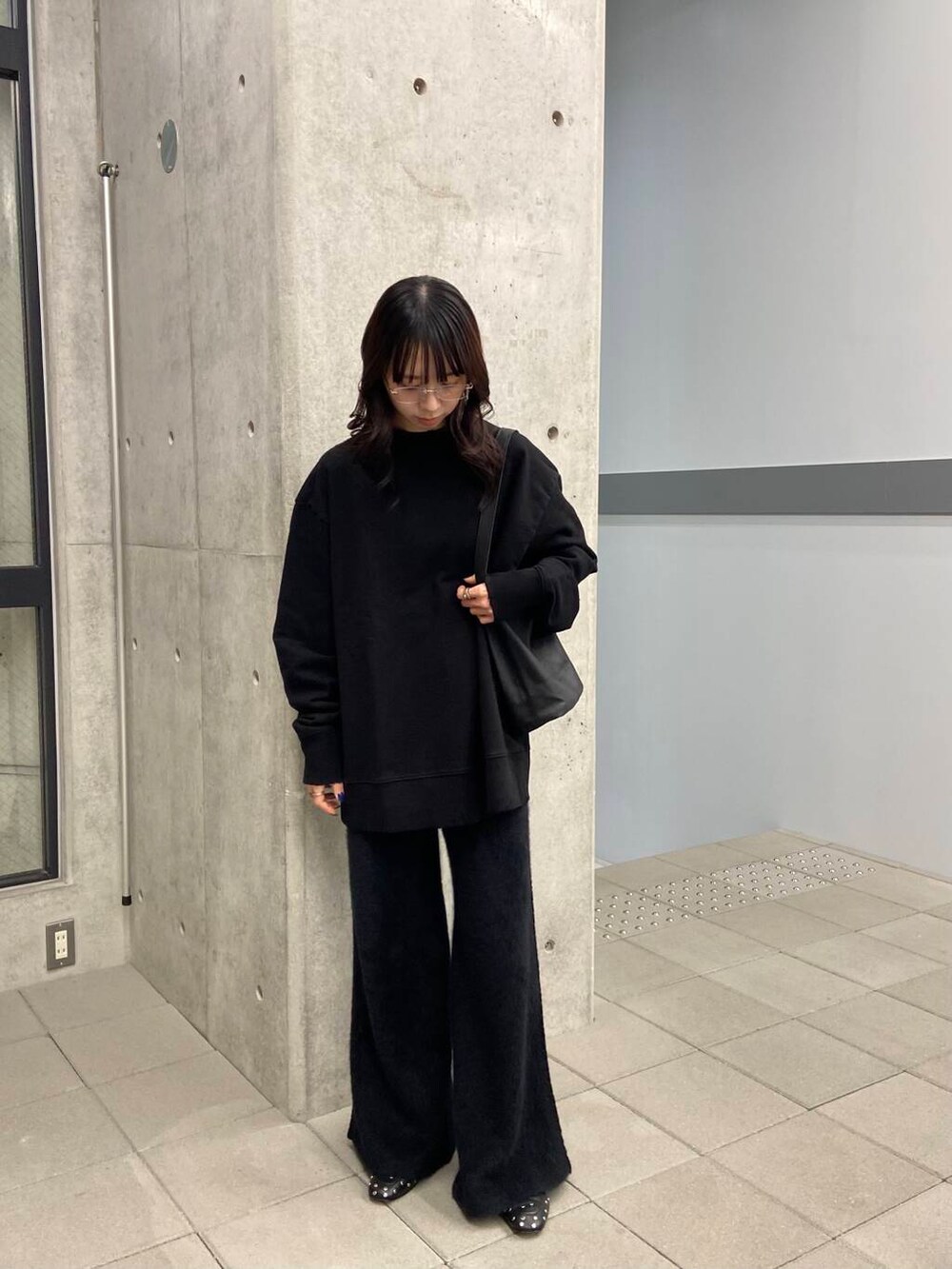 ブラック系のスウェット、ゴールド系のメガネを着用したレディースの冬コーディネートの6枚目の写真