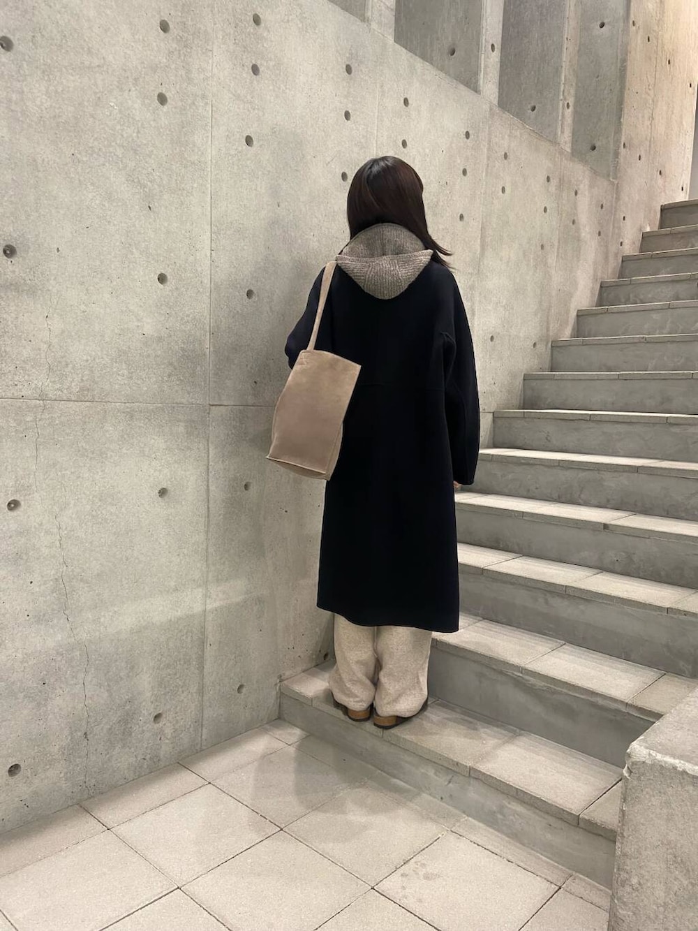 ブラック系のステンカラーコート、グレー系のサンダル、ベージュ系のその他パンツを着用したレディースの冬コーディネートの2枚目の写真