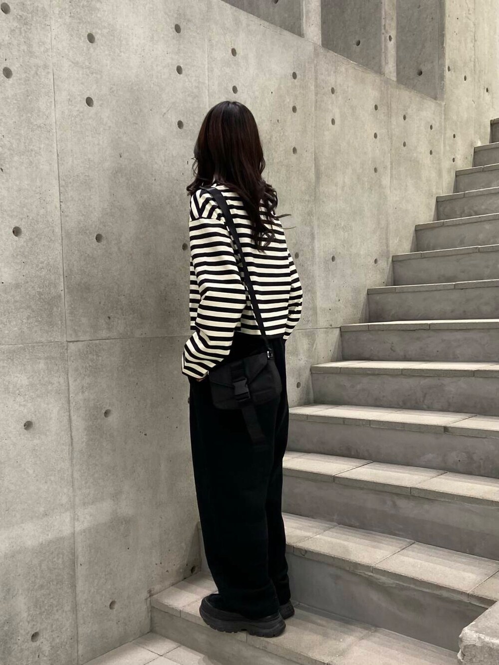 ブラック系のスニーカー、ブラック系のショルダーバッグ、シルバー系のネックレスを着用したレディースの冬コーディネートの2枚目の写真