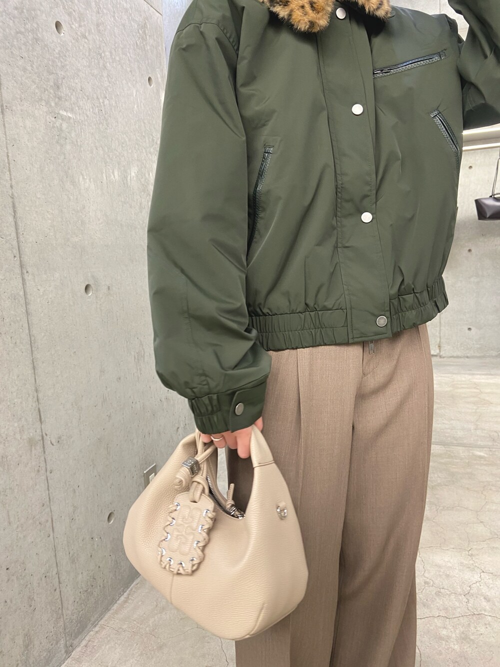 グリーン系のその他アウター、ベージュ系のその他パンツ、ホワイト系のハンドバッグを着用したレディースの冬コーディネートの5枚目の写真