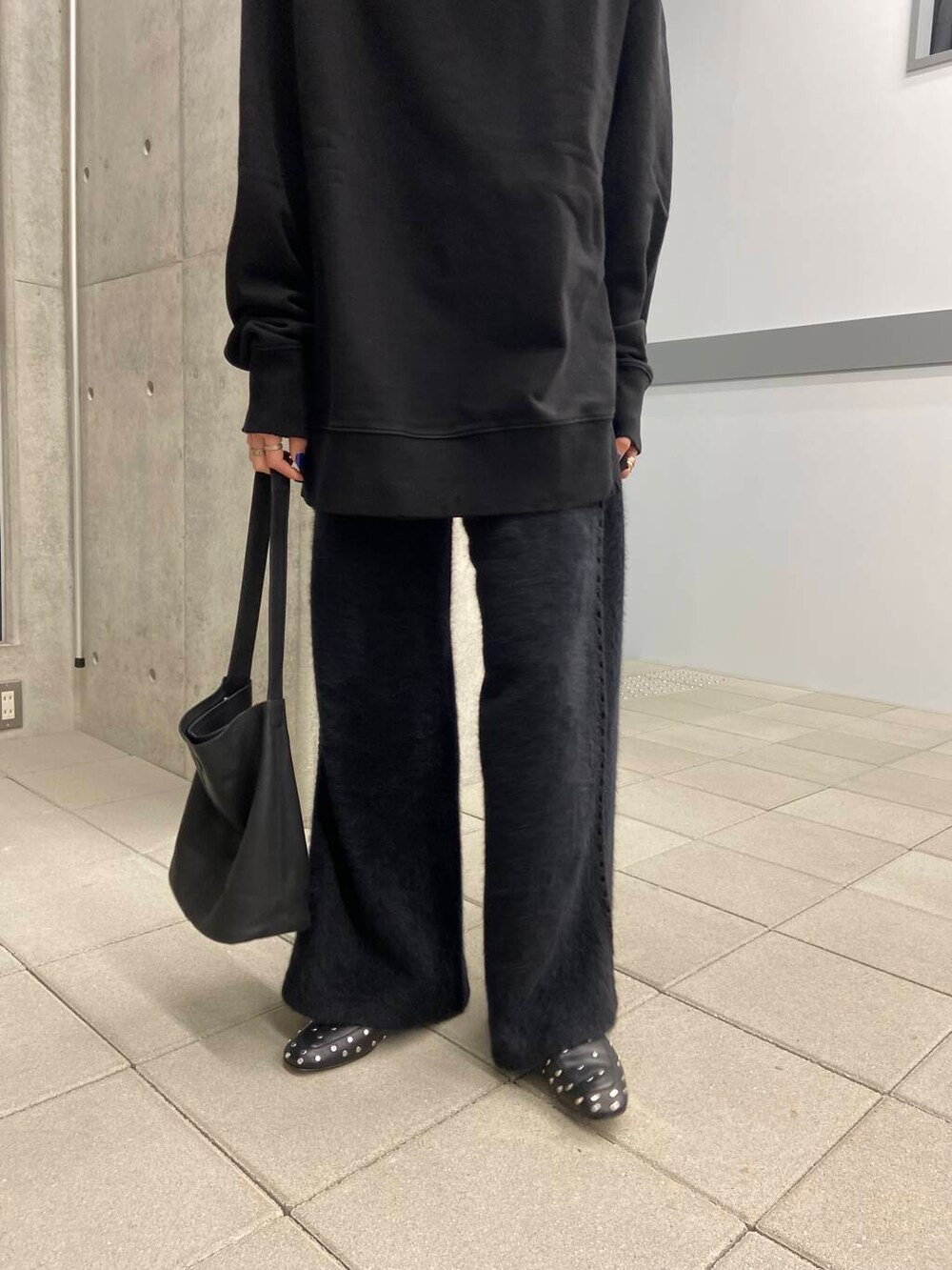 ブラック系のスウェット、ゴールド系のメガネを着用したレディースの冬コーディネートの4枚目の写真