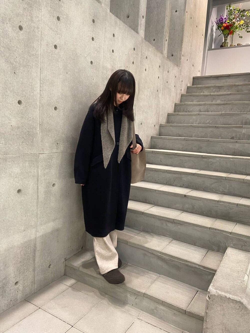 ブラック系のステンカラーコート、グレー系のサンダル、ベージュ系のその他パンツを着用したレディースの冬コーディネートの4枚目の写真