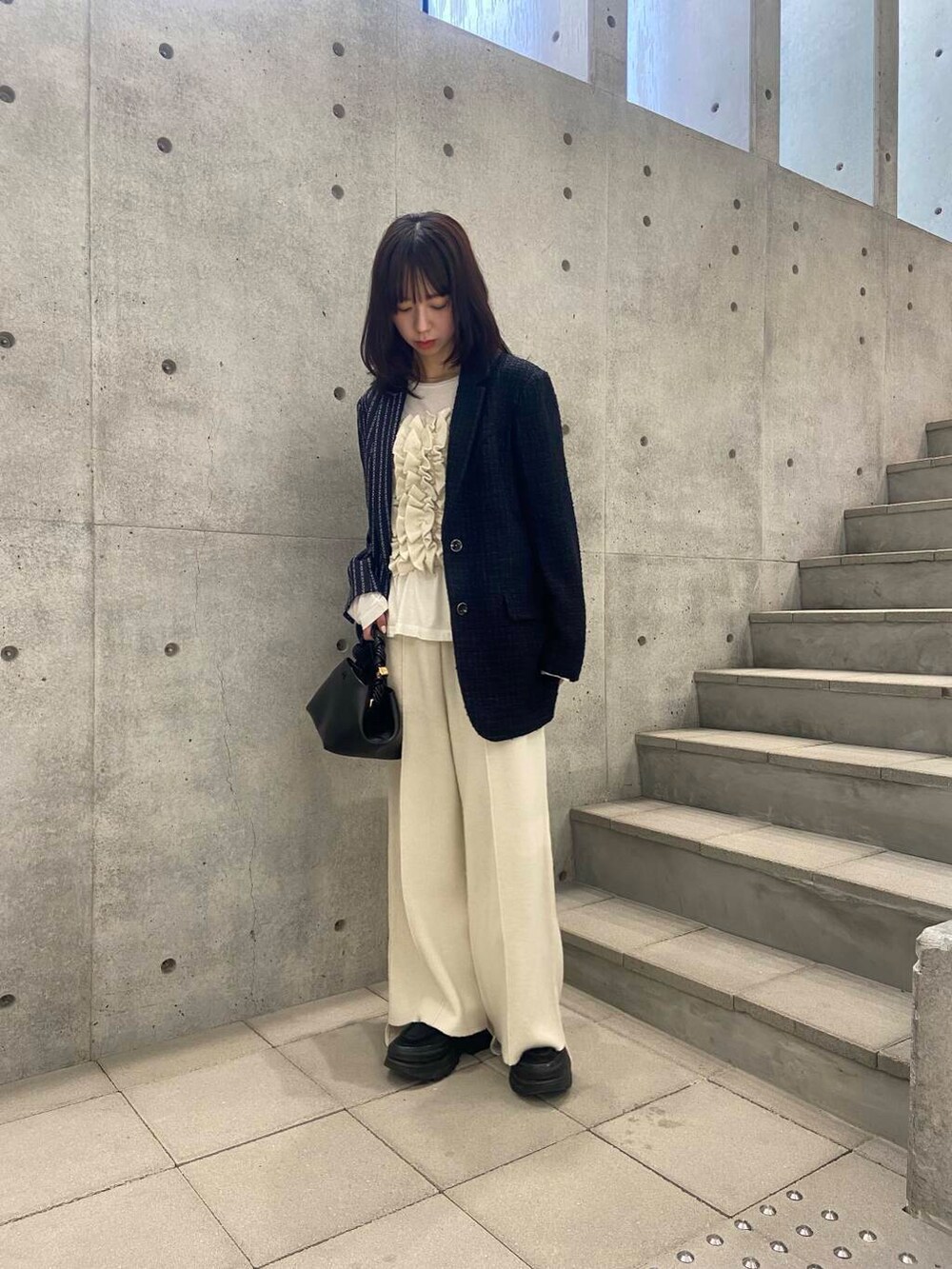 ブラック系のハンドバッグ、ホワイト系のTシャツ/カットソー、グレー系のテーラードジャケットを着用したレディースの秋コーディネートの2枚目の写真