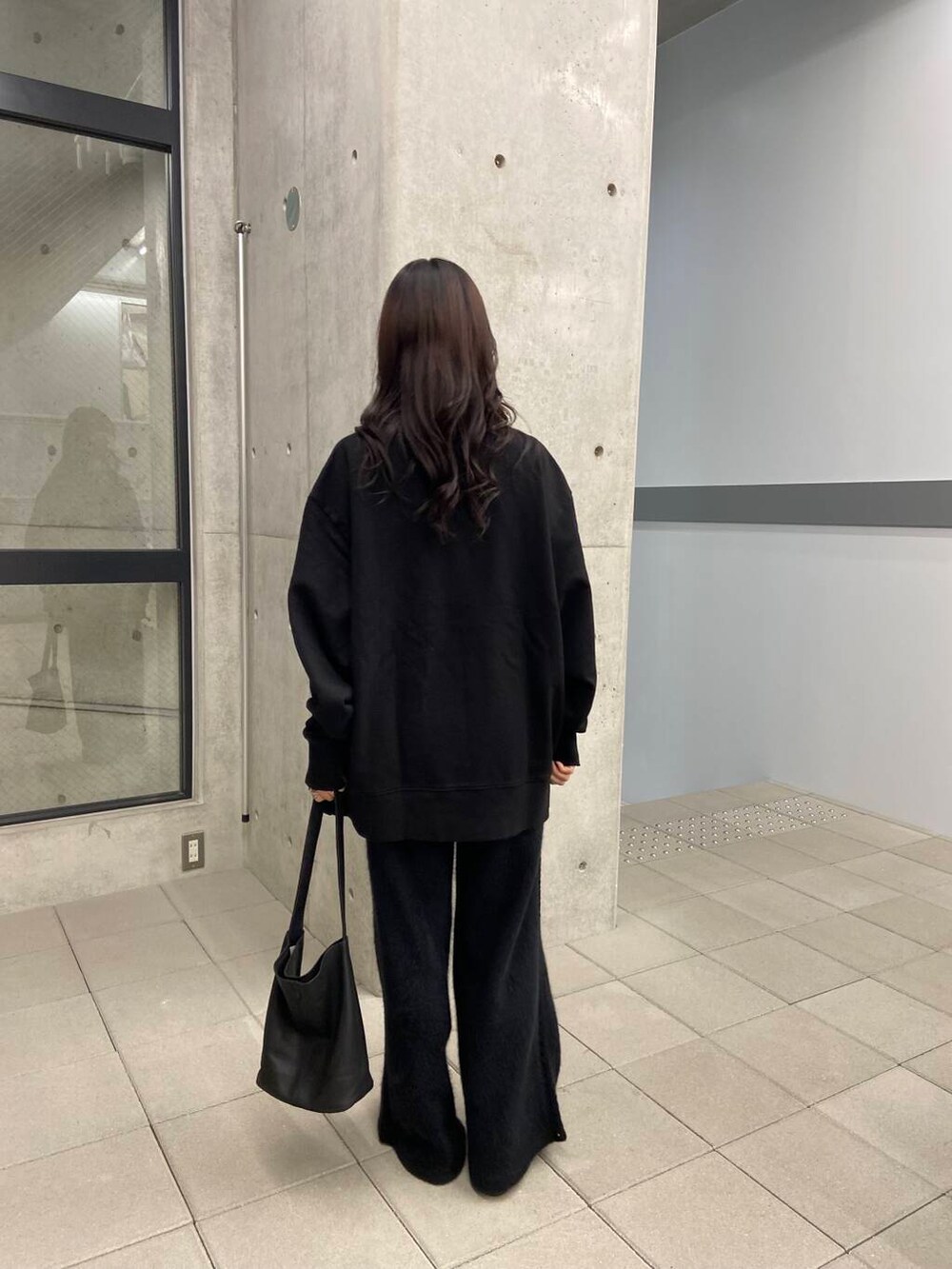 ブラック系のスウェット、ゴールド系のメガネを着用したレディースの冬コーディネートの2枚目の写真