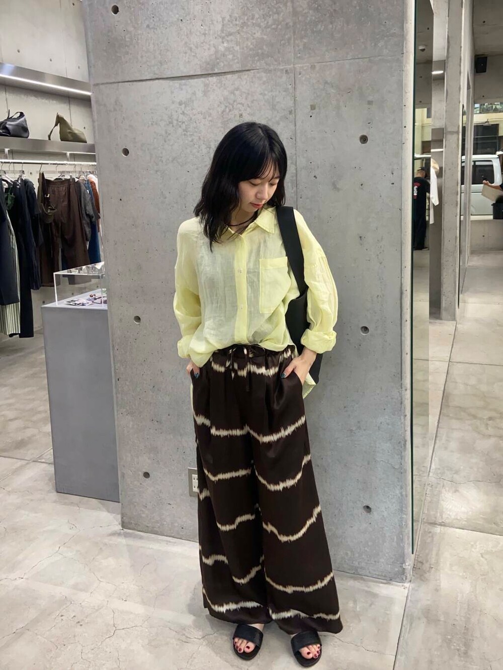 ブラック系のトートバッグ、ブラウン系のその他パンツ、イエロー系のシャツ/ブラウスを着用したレディースの夏コーディネートの2枚目の写真