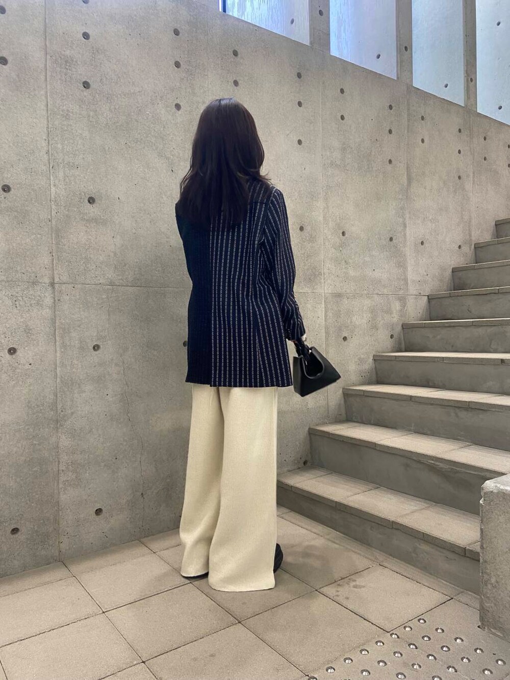 ブラック系のハンドバッグ、ホワイト系のTシャツ/カットソー、グレー系のテーラードジャケットを着用したレディースの秋コーディネートの3枚目の写真