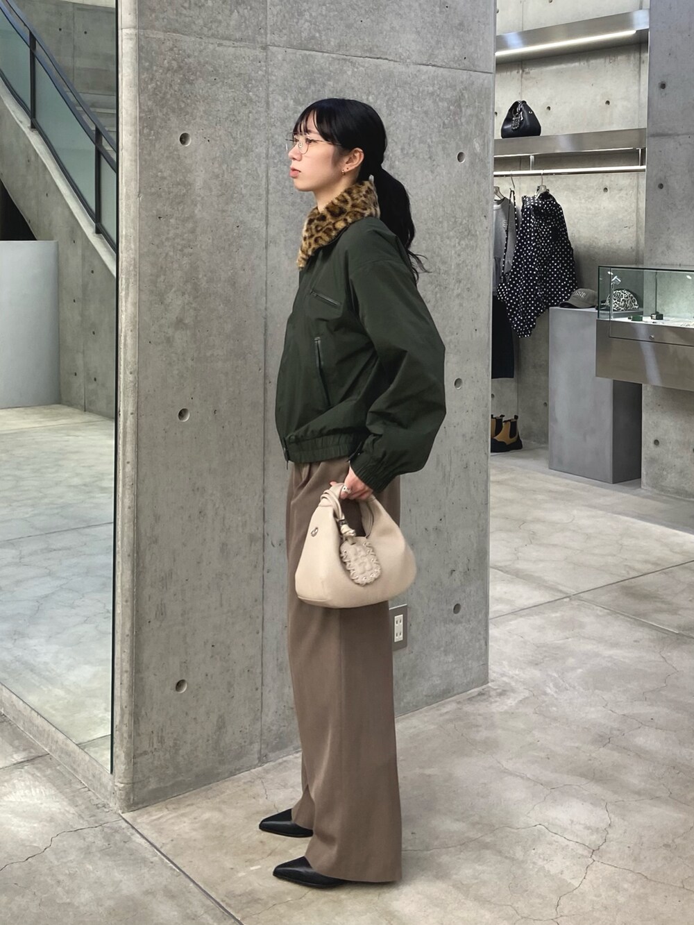 グリーン系のその他アウター、ベージュ系のその他パンツ、ホワイト系のハンドバッグを着用したレディースの冬コーディネートの2枚目の写真