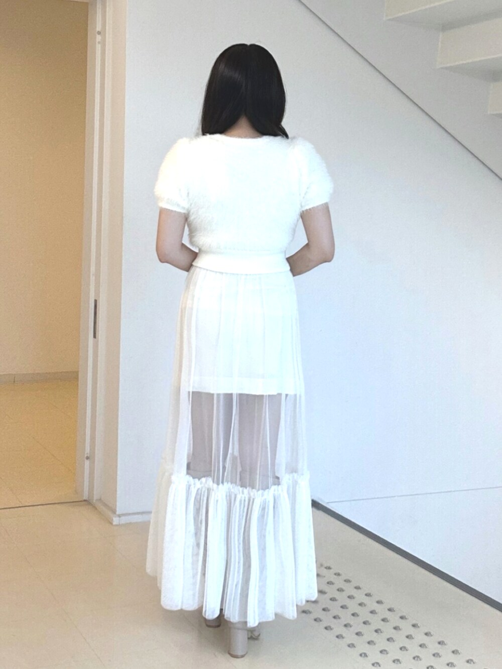 ホワイト系のニット/セーター、ホワイト系のスカート、ベージュ系のブーツを着用したレディースの夏コーディネートの3枚目の写真