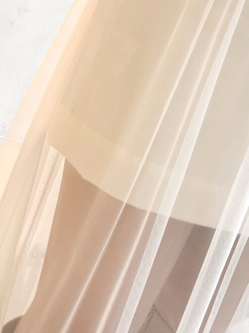 ホワイト系のニット/セーター、ホワイト系のスカート、ベージュ系のブーツを着用したレディースの夏コーディネートの4枚目の写真