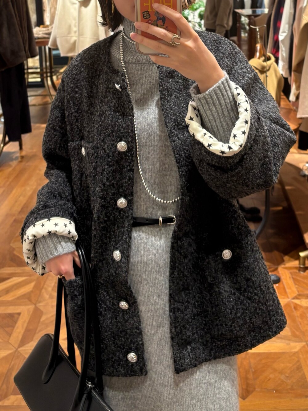 グレー系のノーカラージャケット、グレー系のワンピース、ブラック系のバッグを着用したレディースの秋コーディネートの2枚目の写真