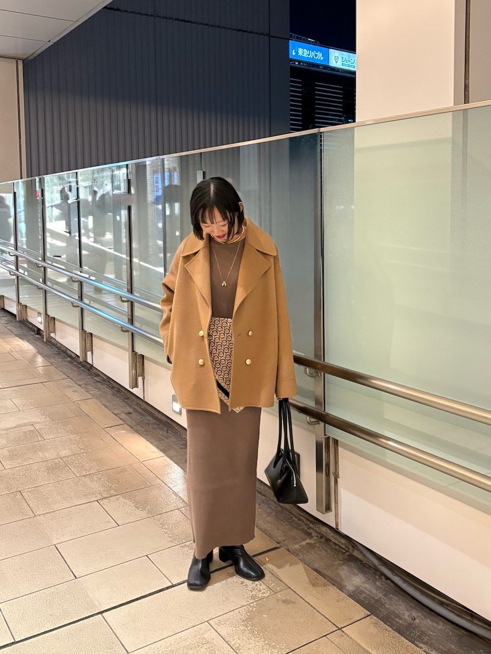 ブラウン系のワンピース、イエロー系のジャケット/アウター、ブラック系のバッグを着用したレディースの冬コーディネートの2枚目の写真