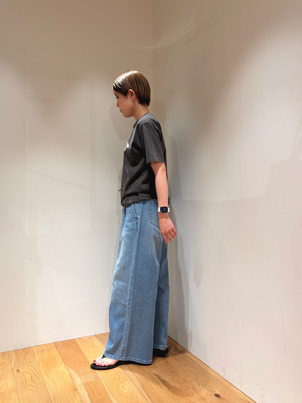 ブルー系のデニムパンツ、ブラック系のサンダル、ブラック系のTシャツ/カットソーを着用したレディースの夏コーディネートの4枚目の写真