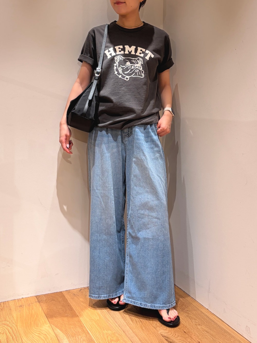 ブルー系のデニムパンツ、ブラック系のサンダル、ブラック系のTシャツ/カットソーを着用したレディースの夏コーディネートの2枚目の写真