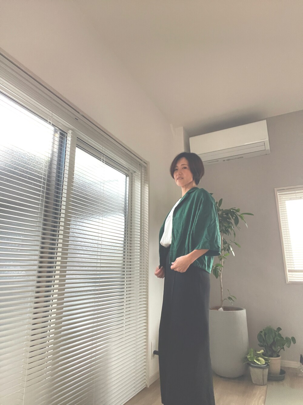 グリーン系のカーディガン/ボレロ、ブラック系のスカート、ホワイト系のTシャツ/カットソーを着用したレディースの秋コーディネートの2枚目の写真