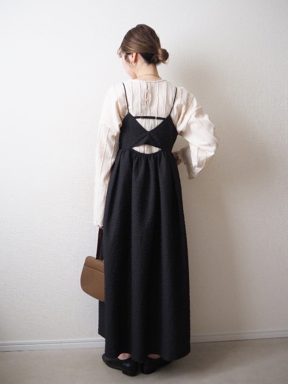 ブラック系のワンピース、ホワイト系のミリタリージャケット、ベージュ系のトートバッグを着用したレディースの冬コーディネートの3枚目の写真