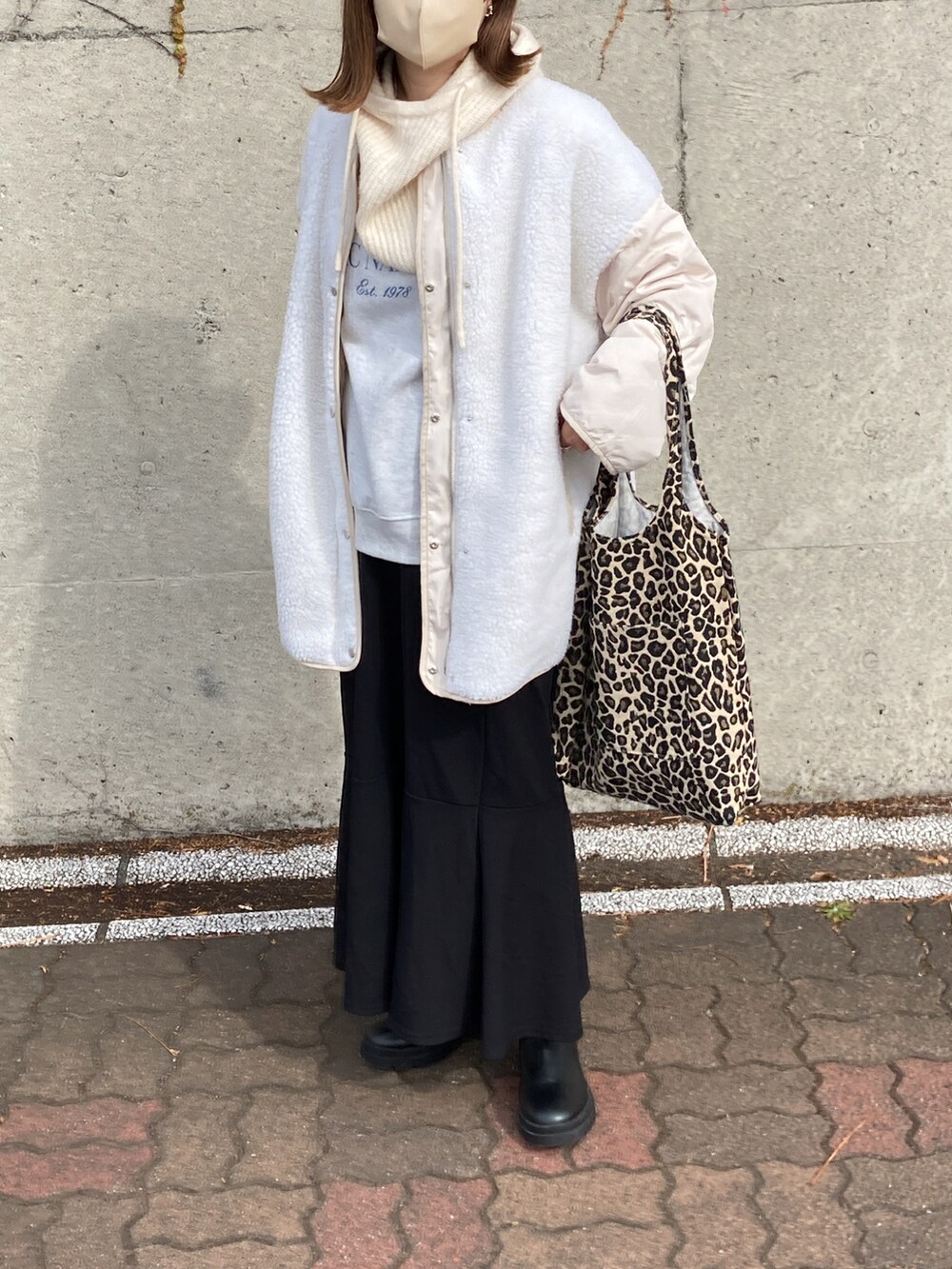 ホワイト系のノーカラージャケット、ブラック系のブーツ、ホワイト系のニットキャップ/ビーニーを着用したレディースの秋コーディネートの2枚目の写真