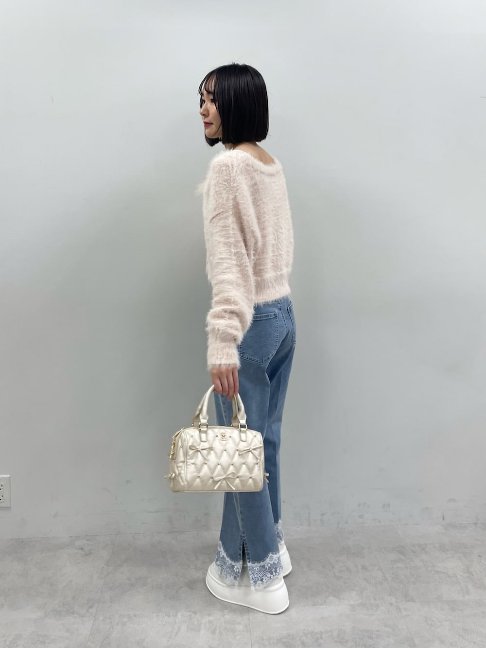ピンク系のカーディガン/ボレロ、ホワイト系のボストンバッグ、ブルー系のデニムパンツを着用したレディースの秋コーディネートの3枚目の写真