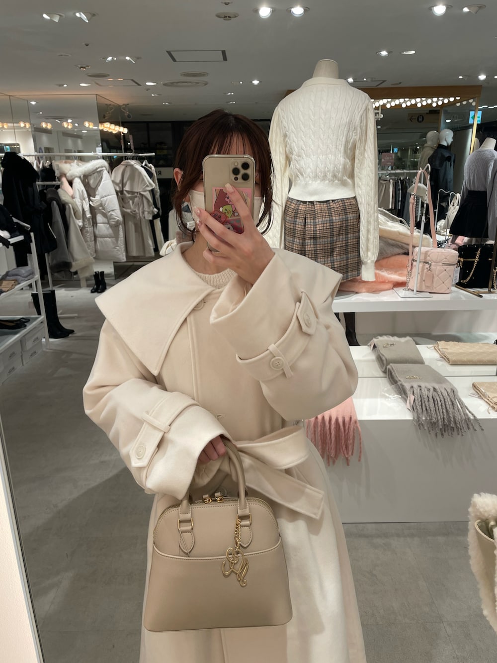 ホワイト系のチェスターコート、ベージュ系のハンドバッグを着用したレディースの冬コーディネートの2枚目の写真