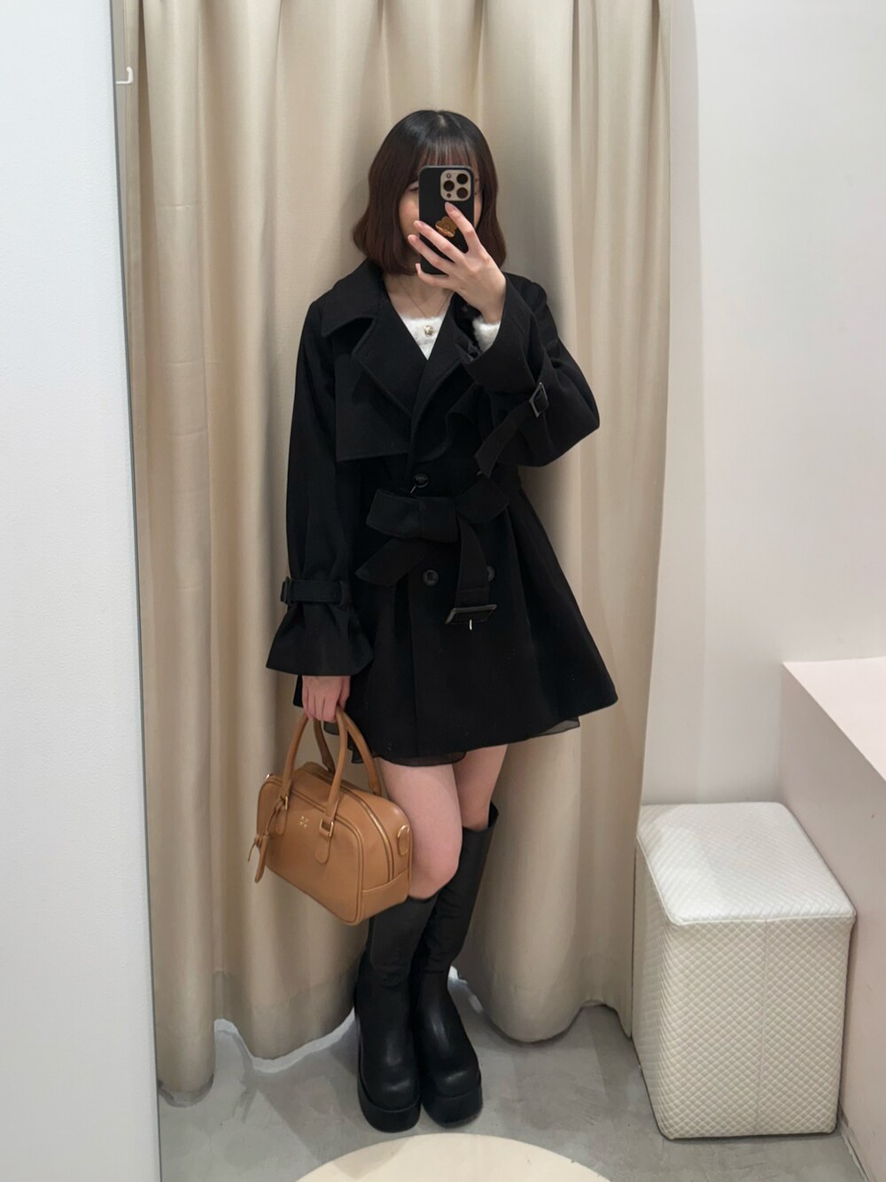 ブラック系のチェスターコート、ブラック系のブーツ、イエロー系のショルダーバッグを着用したレディースの冬コーディネートの2枚目の写真