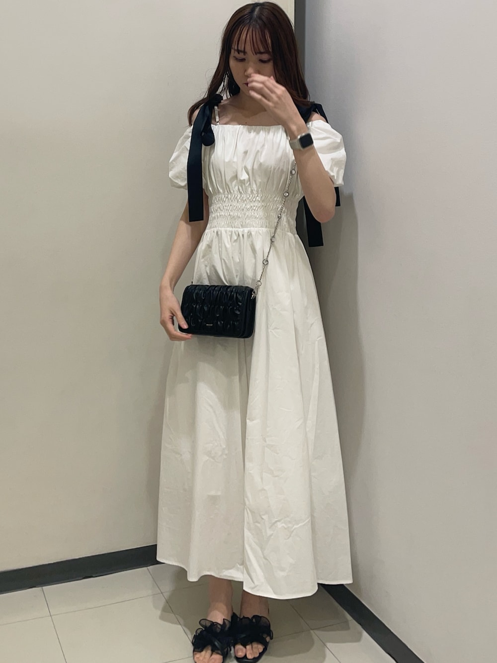 ホワイト系のワンピース、ブラック系のショルダーバッグ、ブラック系のサンダルを着用したレディースの夏コーディネートの2枚目の写真