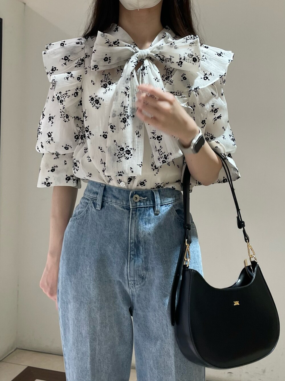 ホワイト系のワンピース、ブルー系のデニムパンツ、ブラック系のショルダーバッグを着用したレディースの春コーディネートの3枚目の写真