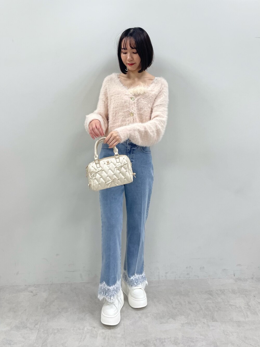 ピンク系のカーディガン/ボレロ、ホワイト系のボストンバッグ、ブルー系のデニムパンツを着用したレディースの秋コーディネートの2枚目の写真