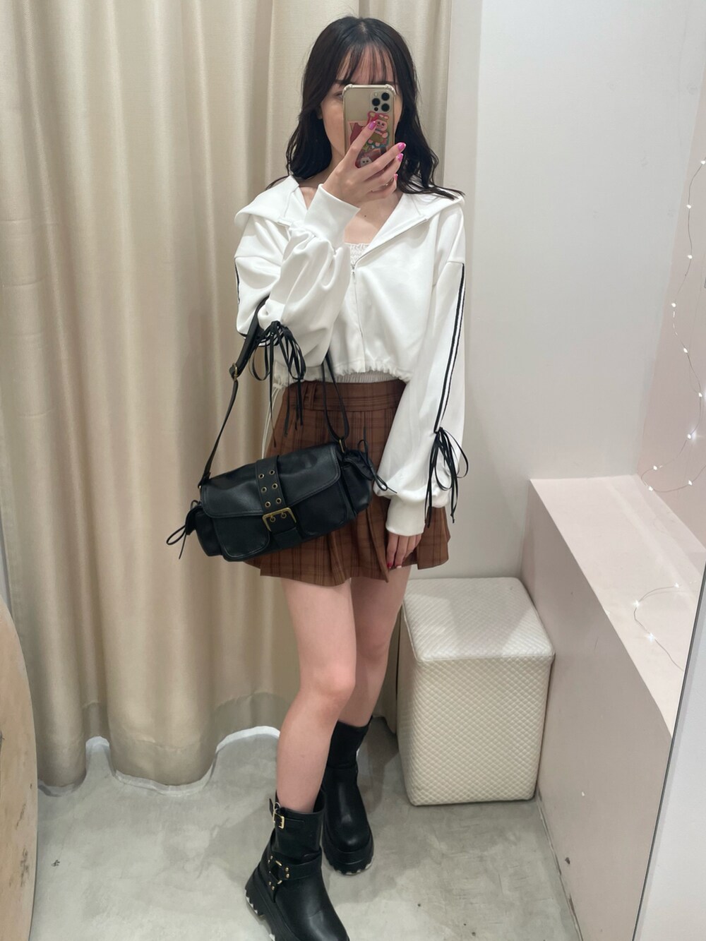 ホワイト系のパーカー、ブラウン系のスカート、ブラック系のショルダーバッグを着用したレディースの秋コーディネートの3枚目の写真