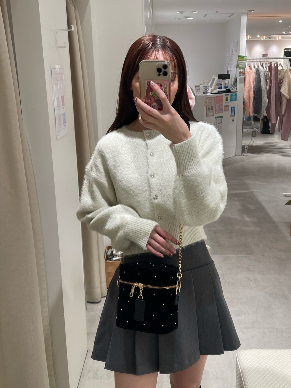 ホワイト系のカーディガン/ボレロ、グレー系のスカート、ブラック系のショルダーバッグを着用したレディースの冬コーディネートの2枚目の写真