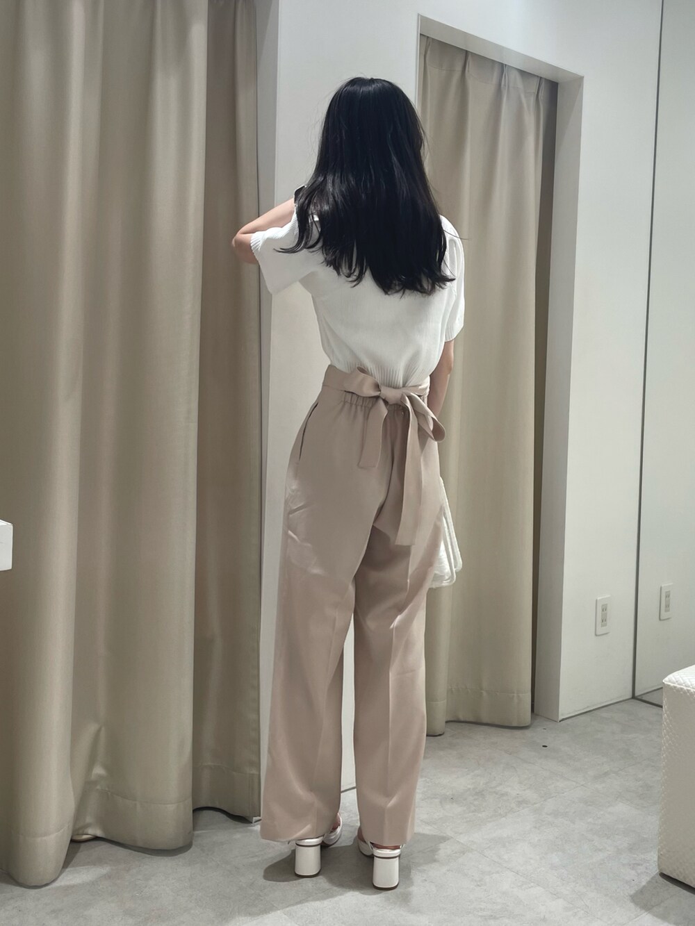 ホワイト系のニット/セーター、ベージュ系のパンツ、ホワイト系のショルダーバッグを着用したレディースの春コーディネートの2枚目の写真