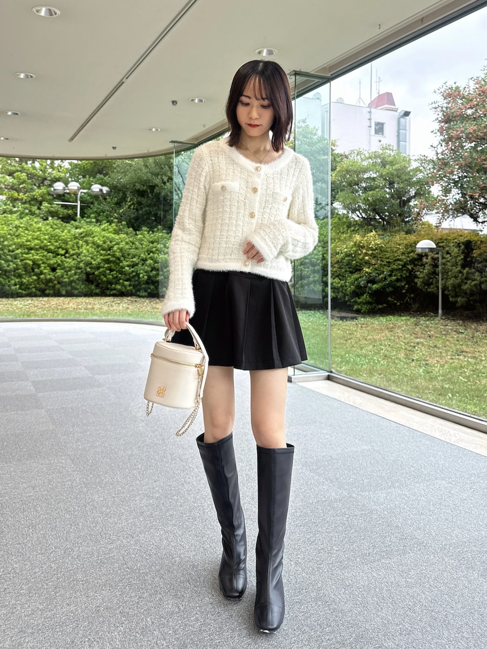 ホワイト系のニット/セーター、ブラック系のスカート、ホワイト系のショルダーバッグを着用したレディースの秋コーディネートの2枚目の写真