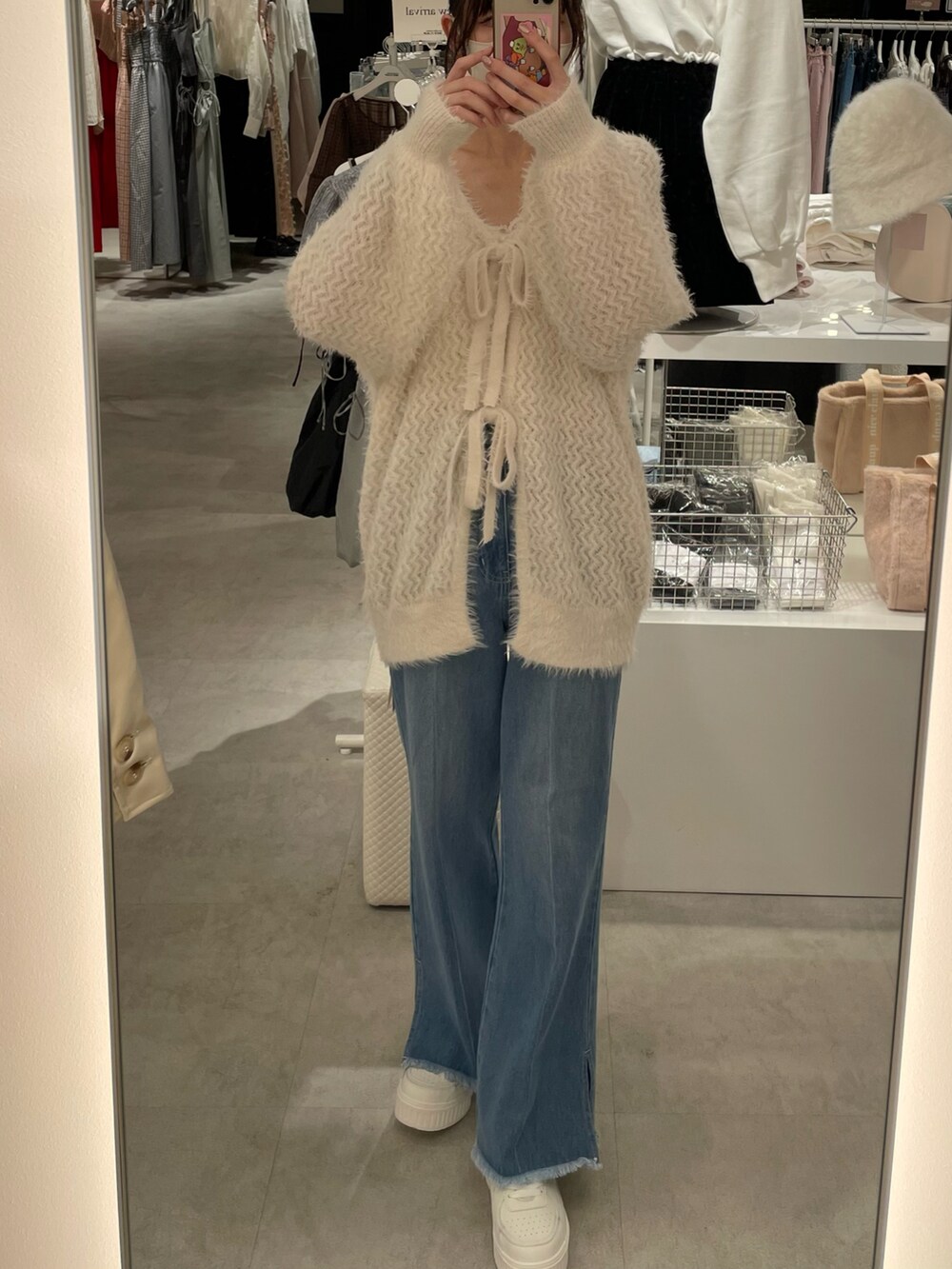 ホワイト系のカーディガン/ボレロ、ブルー系のデニムパンツ、ブラック系のショルダーバッグを着用したレディースの秋コーディネートの2枚目の写真