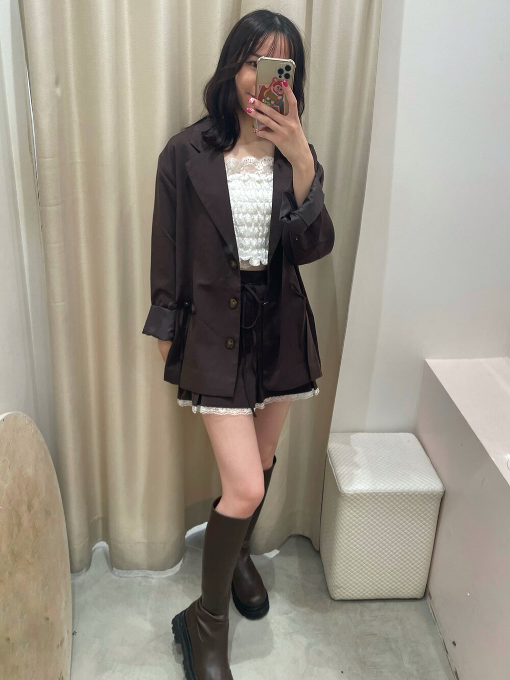 ブラウン系のテーラードジャケット、ブラウン系のスカート、ホワイト系のショルダーバッグを着用したレディースの秋コーディネートの4枚目の写真