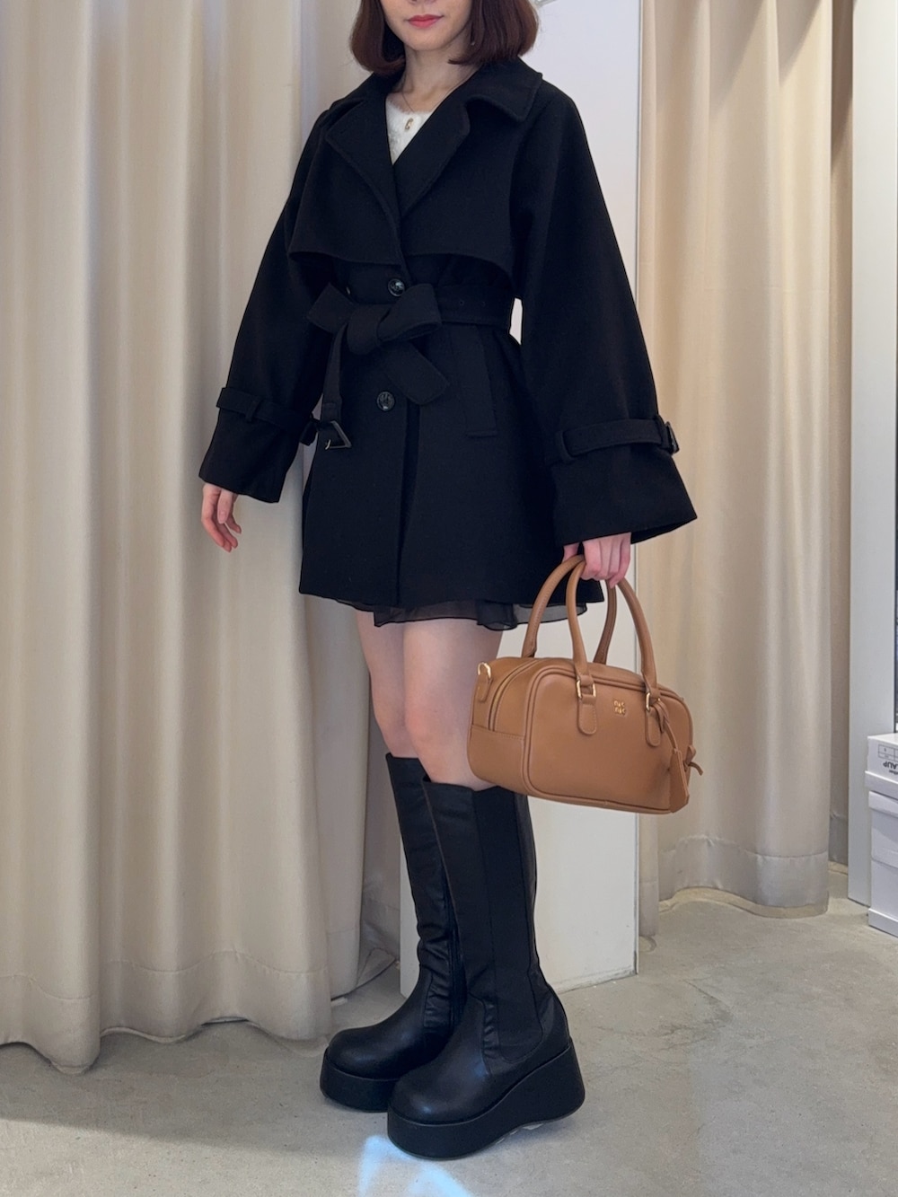 ブラック系のチェスターコート、ブラック系のブーツ、イエロー系のショルダーバッグを着用したレディースの冬コーディネートの3枚目の写真