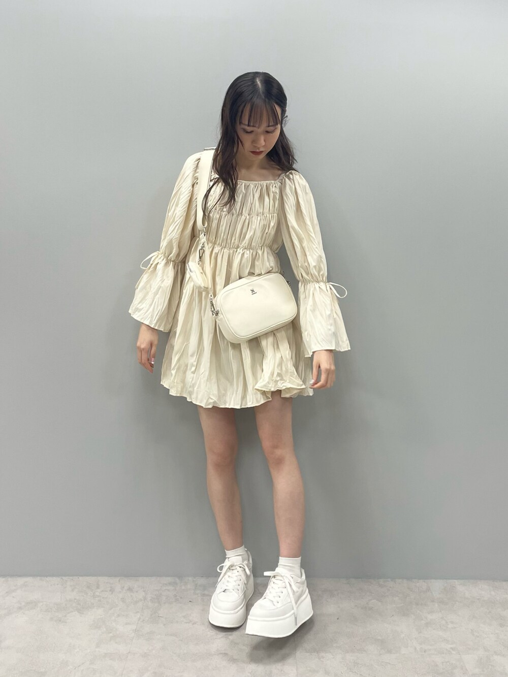 イエロー系のシャツ/ブラウス、ホワイト系のボディバッグ/ウエストポーチ、ホワイト系のスニーカーを着用したレディースの春コーディネートの2枚目の写真