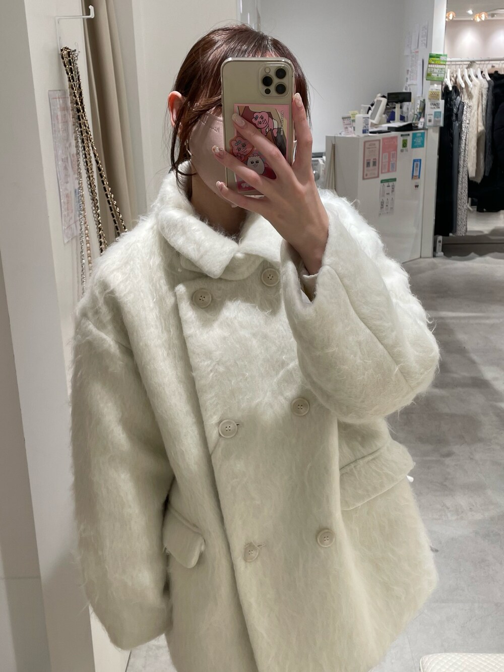 ホワイト系のピーコート、ブラック系のショルダーバッグを着用したレディースの冬コーディネートの2枚目の写真