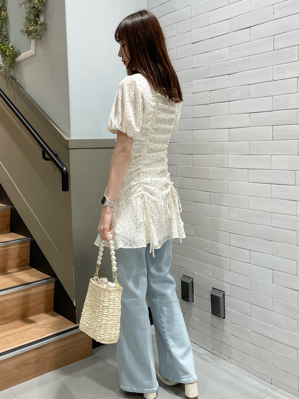 ホワイト系のチュニック、ブルー系のデニムパンツ、ホワイト系のサンダルを着用したレディースの春コーディネートの2枚目の写真