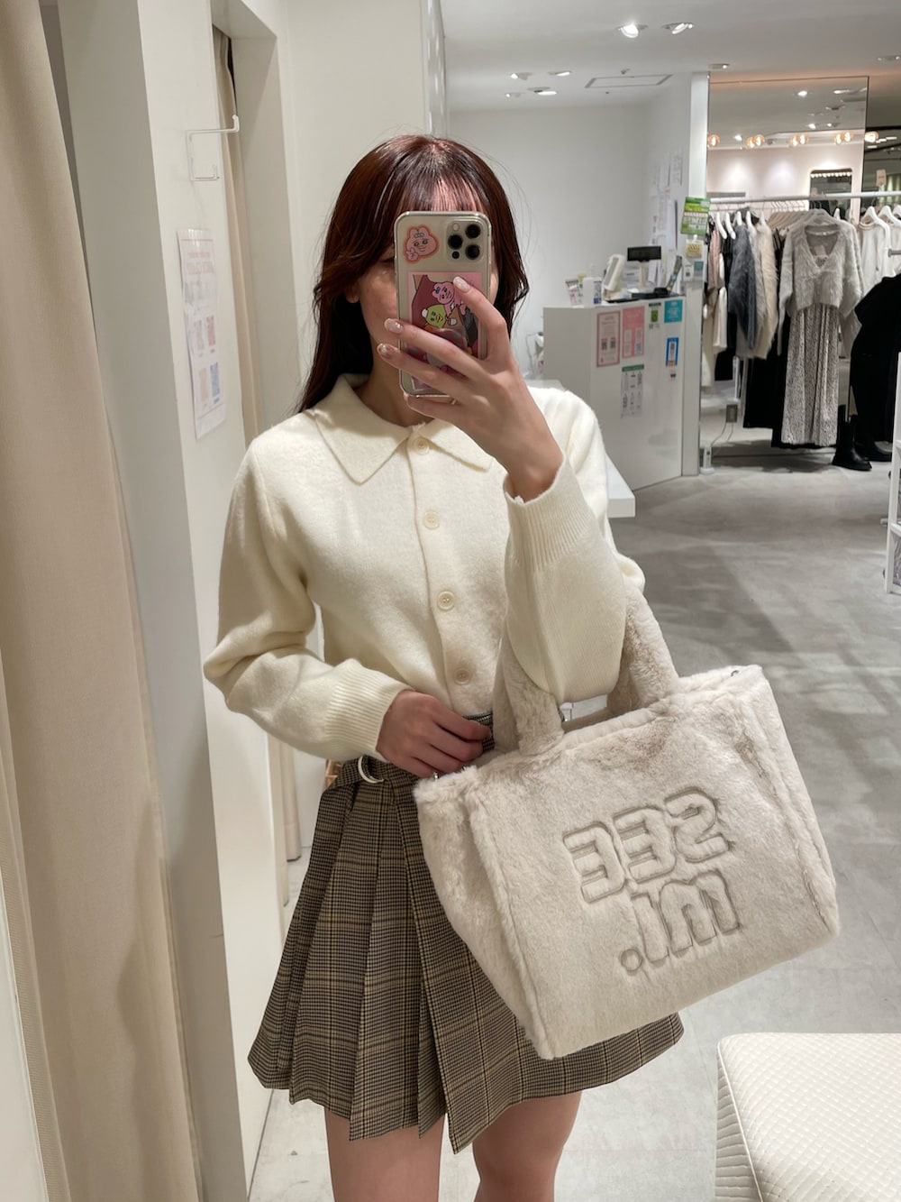 ホワイト系のニット/セーター、ブラウン系のスカート、ホワイト系のトートバッグを着用したレディースの冬コーディネートの2枚目の写真