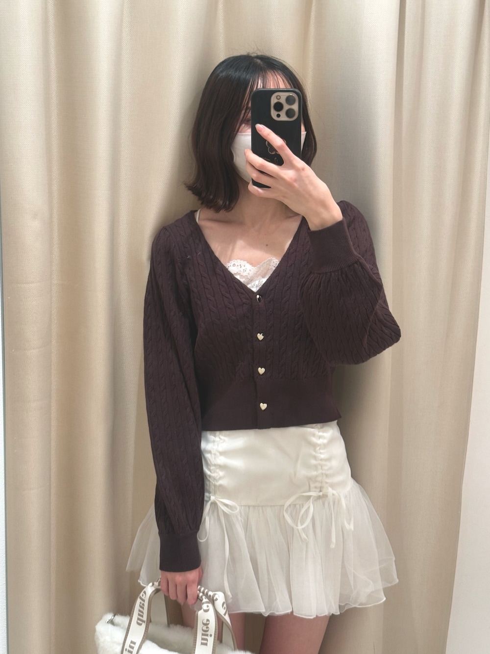 ブラウン系のカーディガン/ボレロ、ホワイト系のトートバッグ、ホワイト系のスカートを着用したレディースの秋コーディネートの2枚目の写真