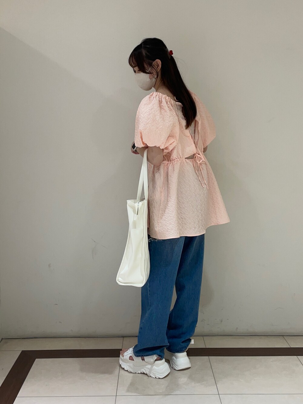 ピンク系のチュニック、ブルー系のデニムパンツ、ホワイト系のサンダルを着用したレディースの夏コーディネートの2枚目の写真