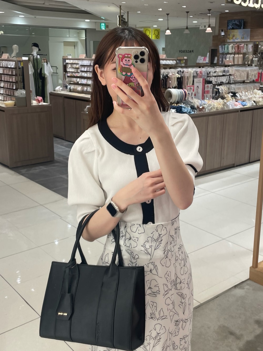 ホワイト系のニット/セーター、ホワイト系のスカート、ブラック系のショルダーバッグを着用したレディースの春コーディネートの2枚目の写真