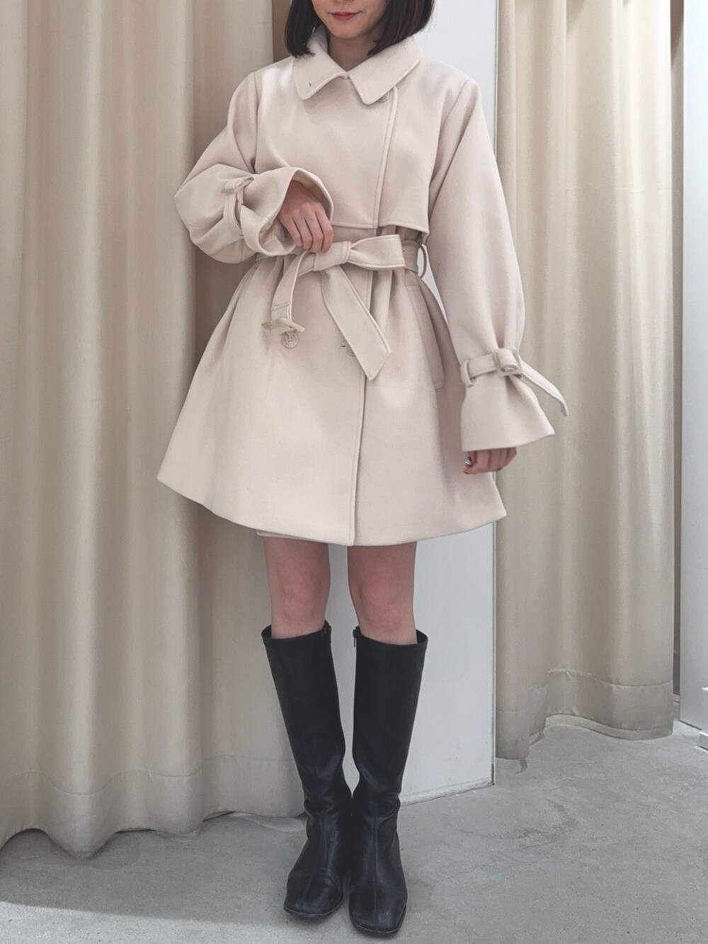 ホワイト系のチェスターコートを着用したレディースの冬コーディネートの2枚目の写真
