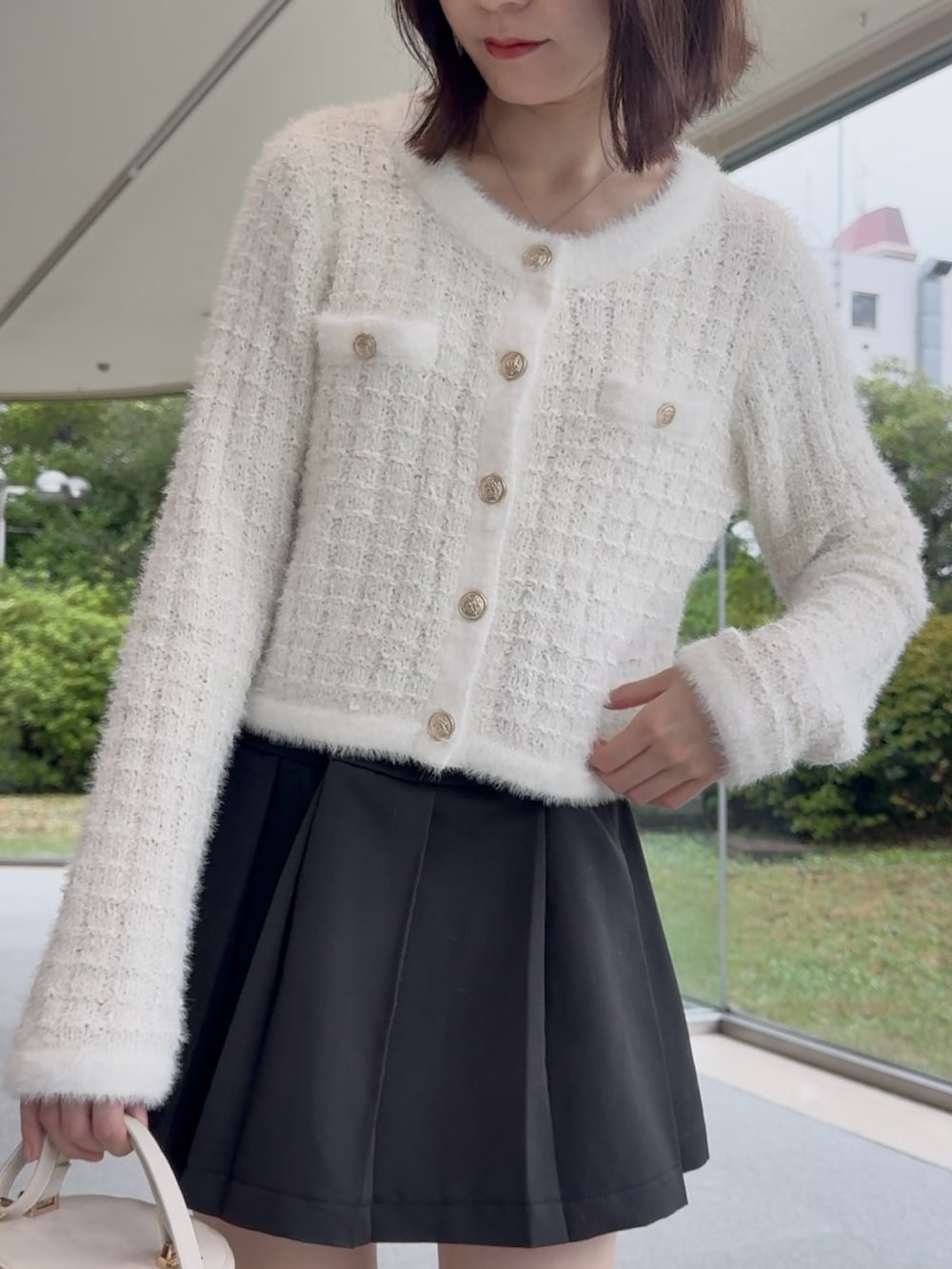 ホワイト系のニット/セーター、ブラック系のスカート、ホワイト系のショルダーバッグを着用したレディースの秋コーディネートの4枚目の写真