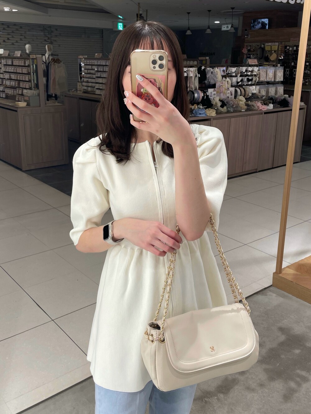 ホワイト系のカーディガン/ボレロ、ブルー系のデニムパンツ、ベージュ系のショルダーバッグを着用したレディースの春コーディネートの2枚目の写真