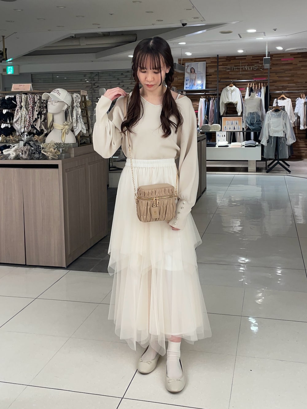 ホワイト系のニット/セーター、ホワイト系のスカート、ベージュ系のショルダーバッグを着用したレディースの春コーディネートの2枚目の写真