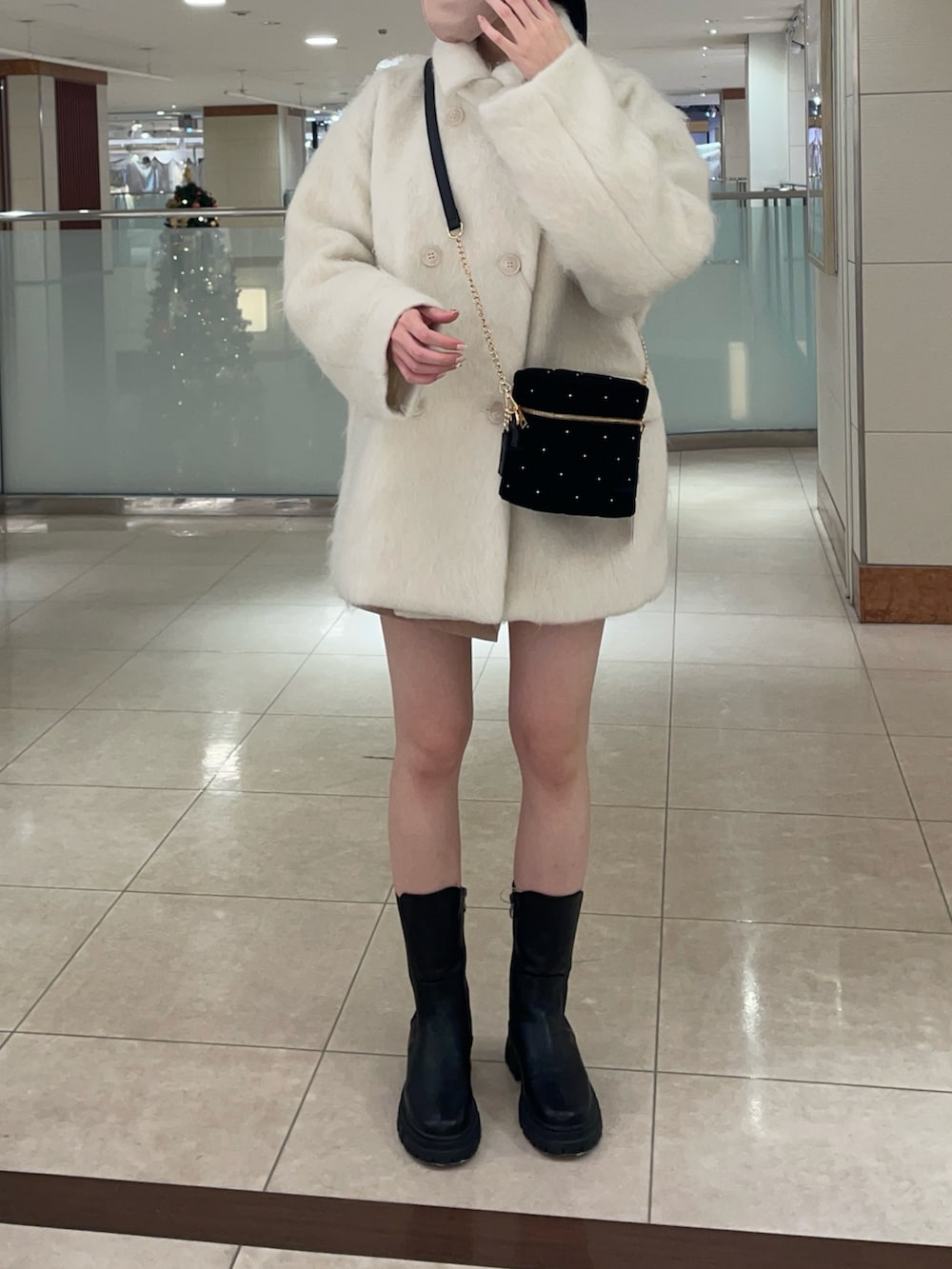 ホワイト系のピーコート、ブラック系のショルダーバッグを着用したレディースの冬コーディネートの3枚目の写真