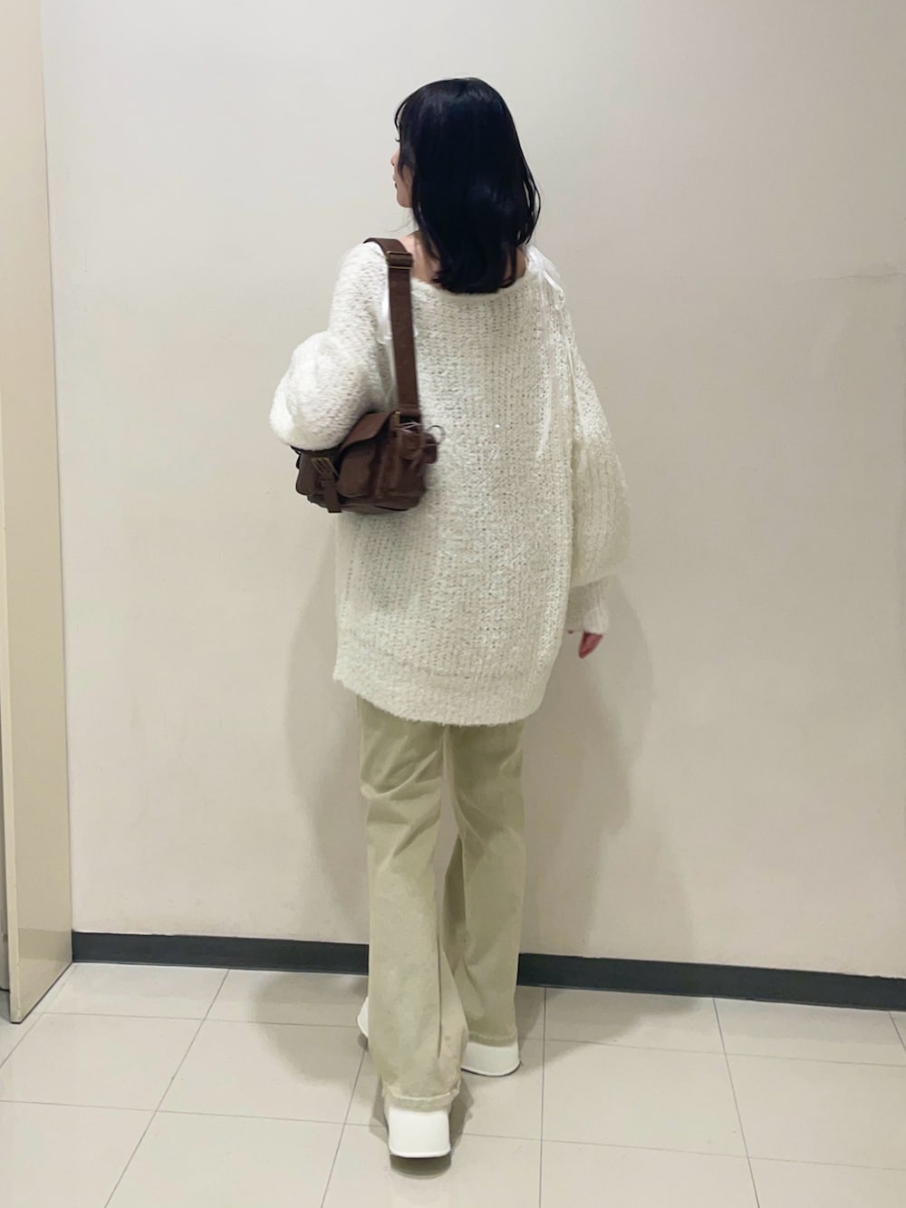 ホワイト系のニット/セーター、ブルー系のデニムパンツ、ホワイト系のスニーカーを着用したレディースの夏コーディネートの2枚目の写真