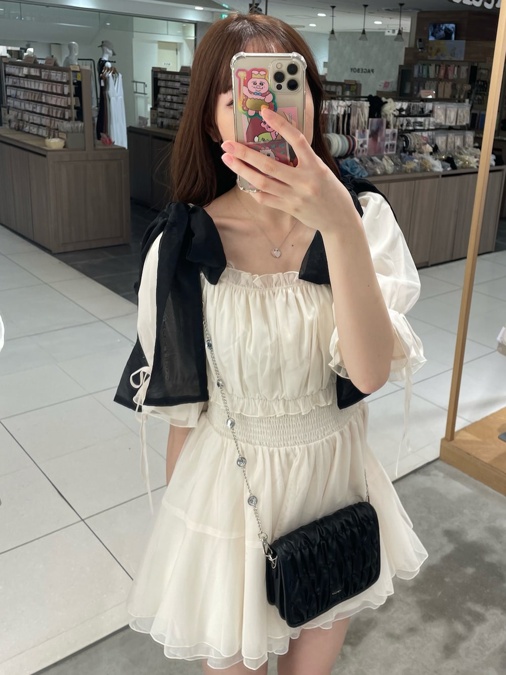 ホワイト系のシャツ/ブラウス、ブラック系のショルダーバッグ、ゴールド系のサンダルを着用したレディースの夏コーディネートの3枚目の写真