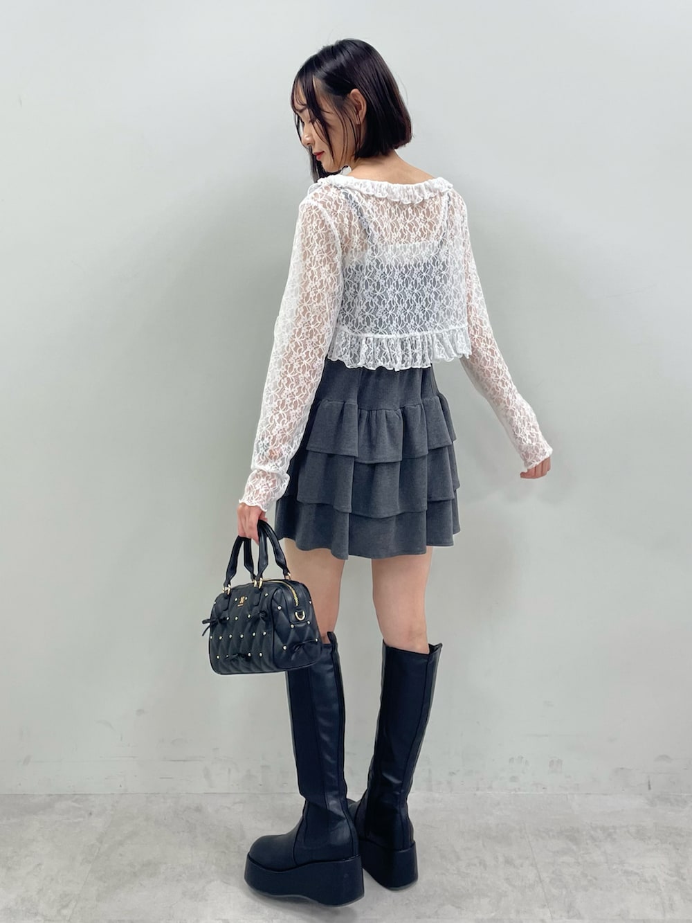 グレー系のワンピース、ブラック系のブーツ、ブラック系のボストンバッグを着用したレディースの秋コーディネートの2枚目の写真